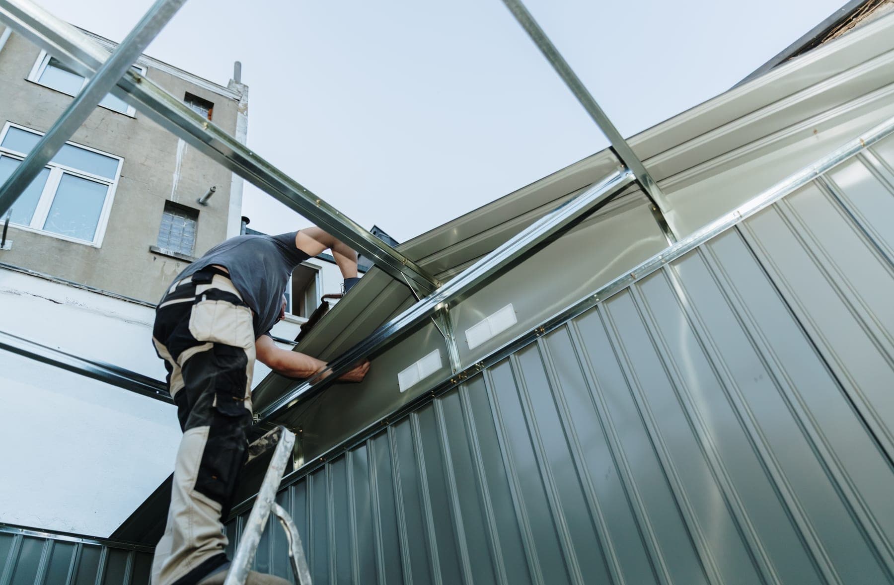 Worker installing sheeting on a large glazed structure